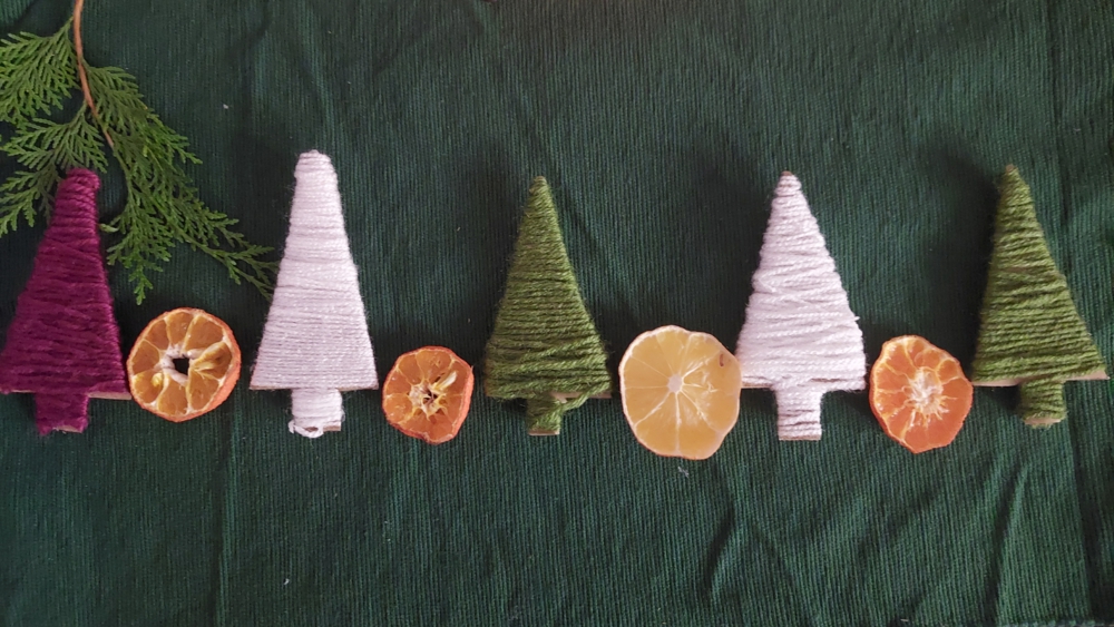 Weihnachtsgirlande aus Tannenbäumen und Orangen, die mit Wolle umwickelt sind