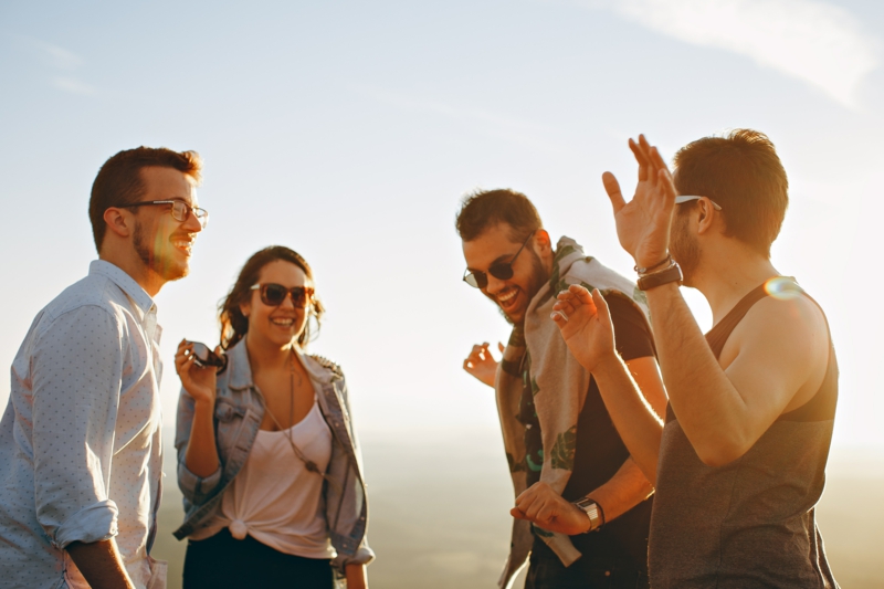 vier Freunde praktizieren Lachyoga im Freien